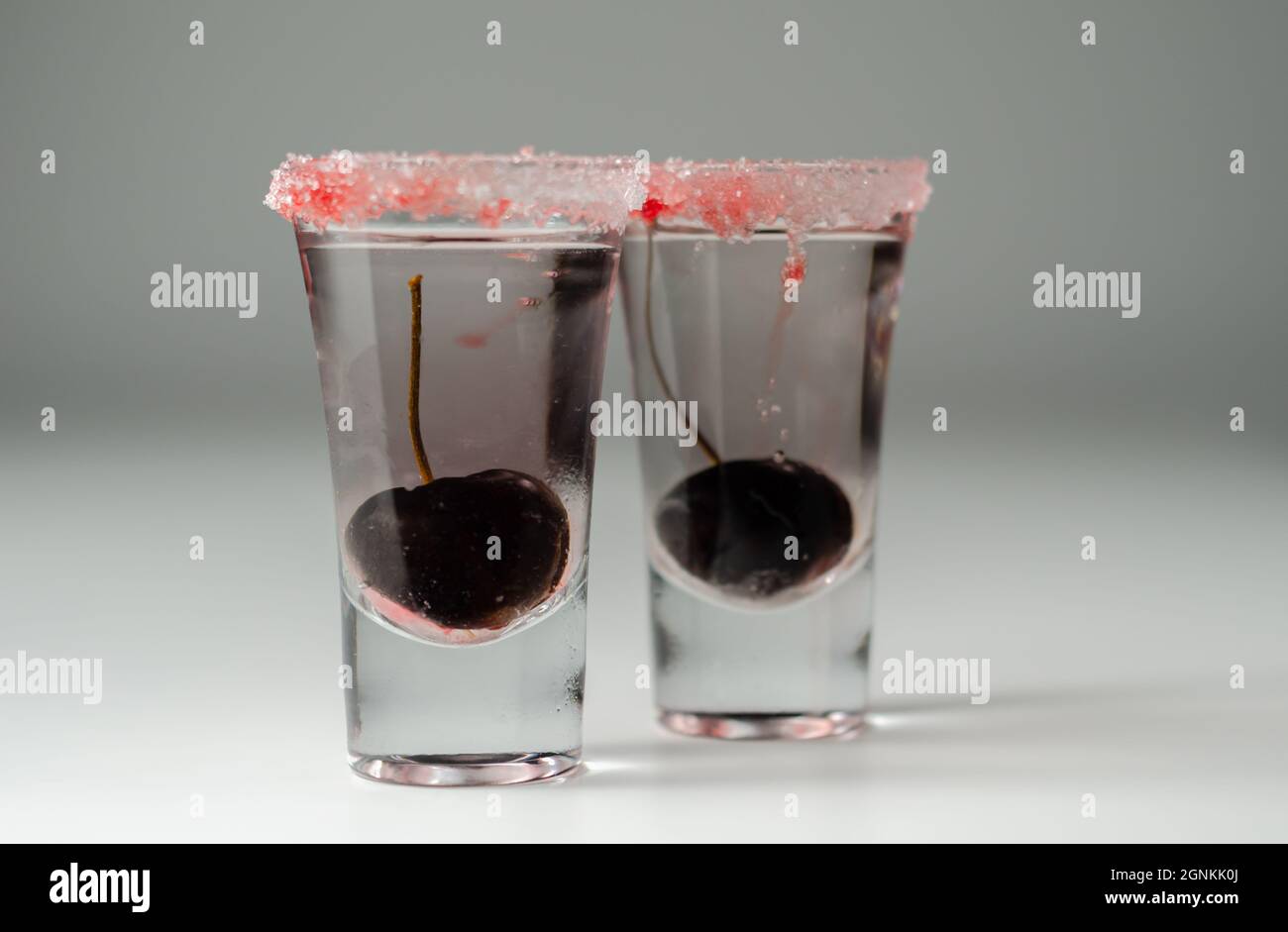 Bevanda a base di vodka, liquore trasparente alla ciliegia e sciroppo in  bicchiere da bibita, decorata con ciliegia fresca e zucchero rosso, bevanda  dolce Foto stock - Alamy