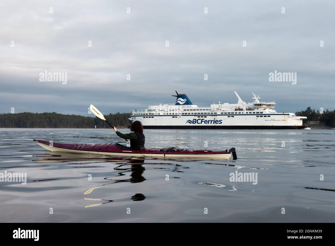 Avventurosa donna in kayak da mare con BC Ferries Boat dietro a Swartz Bay Foto Stock