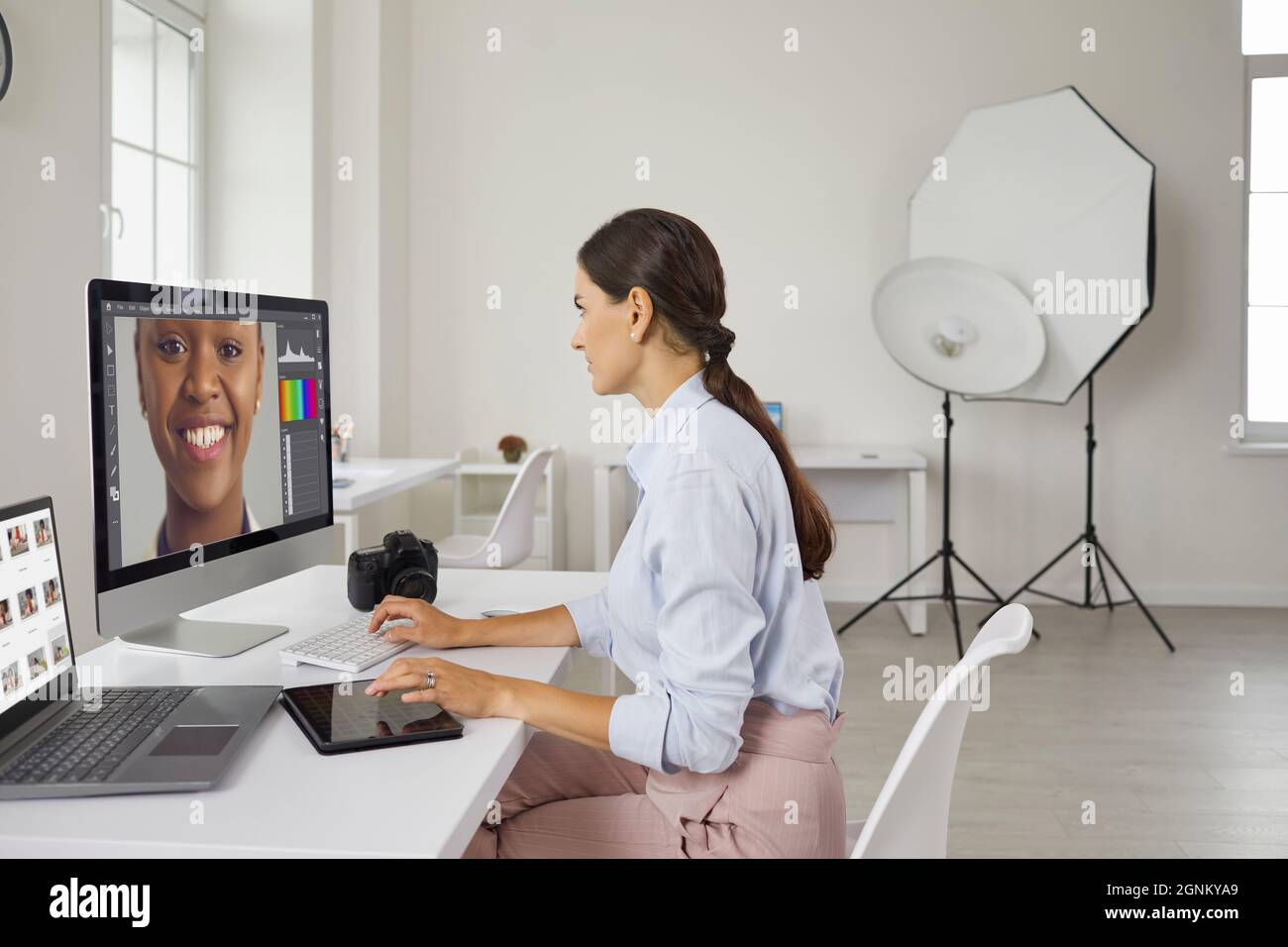 Fotografo che modifica le immagini su un computer mentre lavora in un moderno studio fotografico Foto Stock