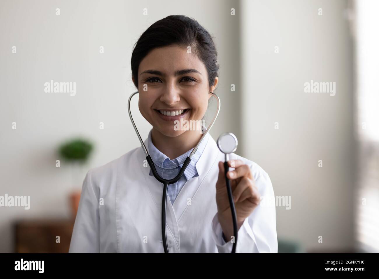 Felice sorridente giovane medico indiano testa ritratto girato Foto Stock