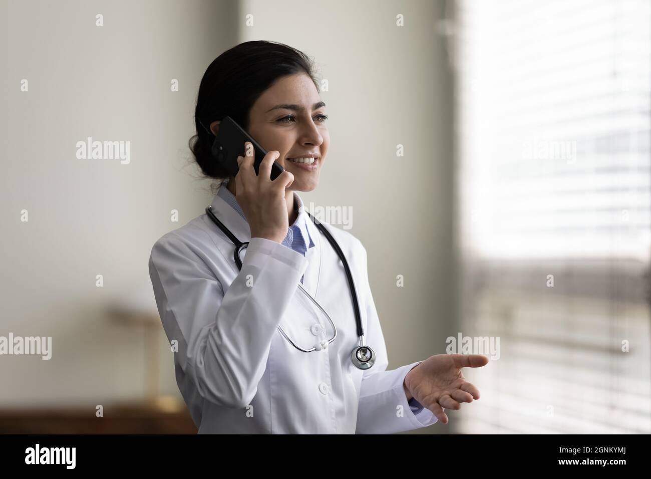 Felice medico indiano che dà la consultazione telefonica, parlando con il paziente Foto Stock