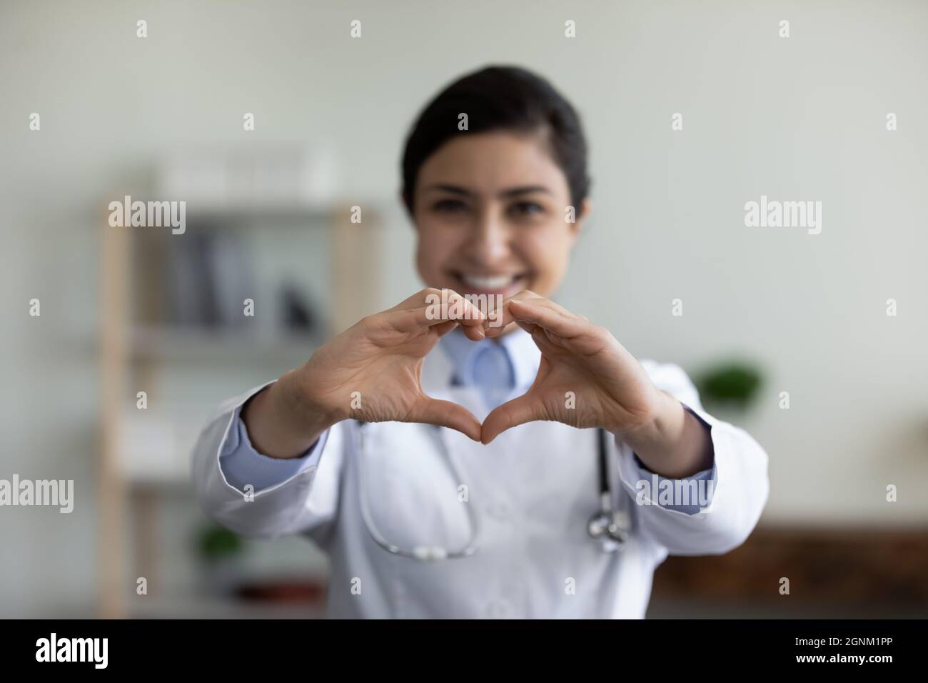 Felice medico indiano GP che mostra la forma del cuore del dito alla macchina fotografica Foto Stock