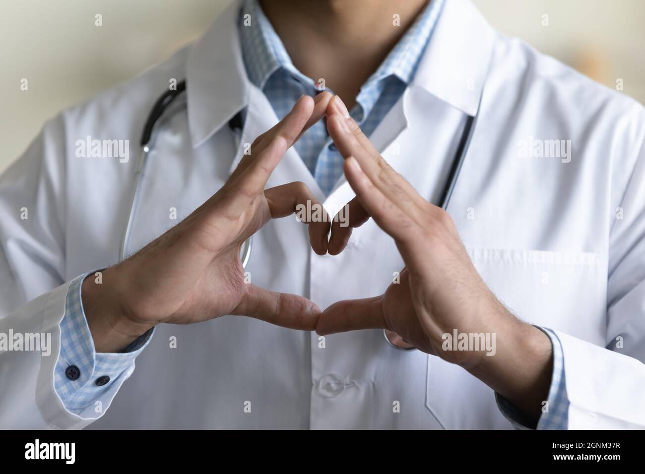 Medico giovane maschio GP che fa la mano e il cuore del dito forma Foto Stock