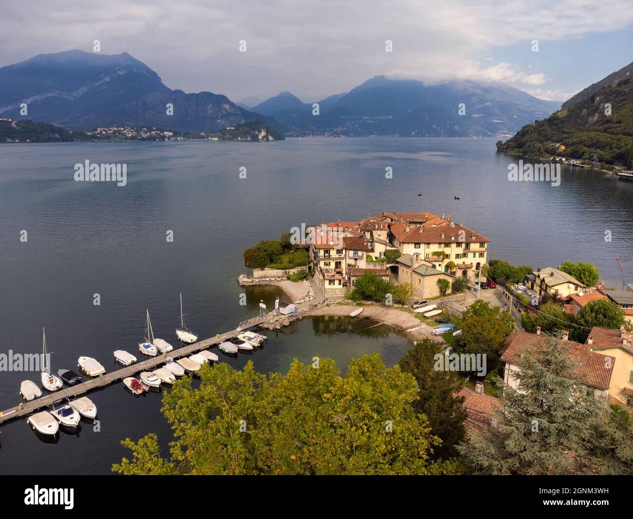 Piccolo villaggio situato su una penisola del Lago di Como vicino ad un porto turistico con barche ormeggiate - Aerial View, Lierna, Lombardia, Italia Foto Stock