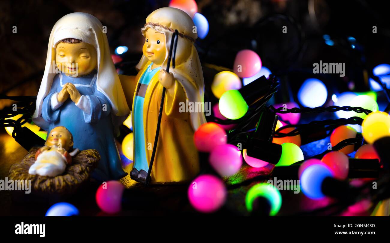 Sfondo per Natale. Figure del portale di Betlemme: San Giuseppe, Vergine Maria e Gesù Bambino con luci colorate sullo sfondo. Sacra Famiglia. Spazio copia Foto Stock