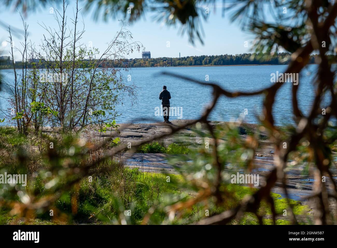 Helsinki / Finlandia - 26 SETTEMBRE 2021: Un solo uomo medio-orientale in piedi sulla riva guardando il mare. Foto Stock
