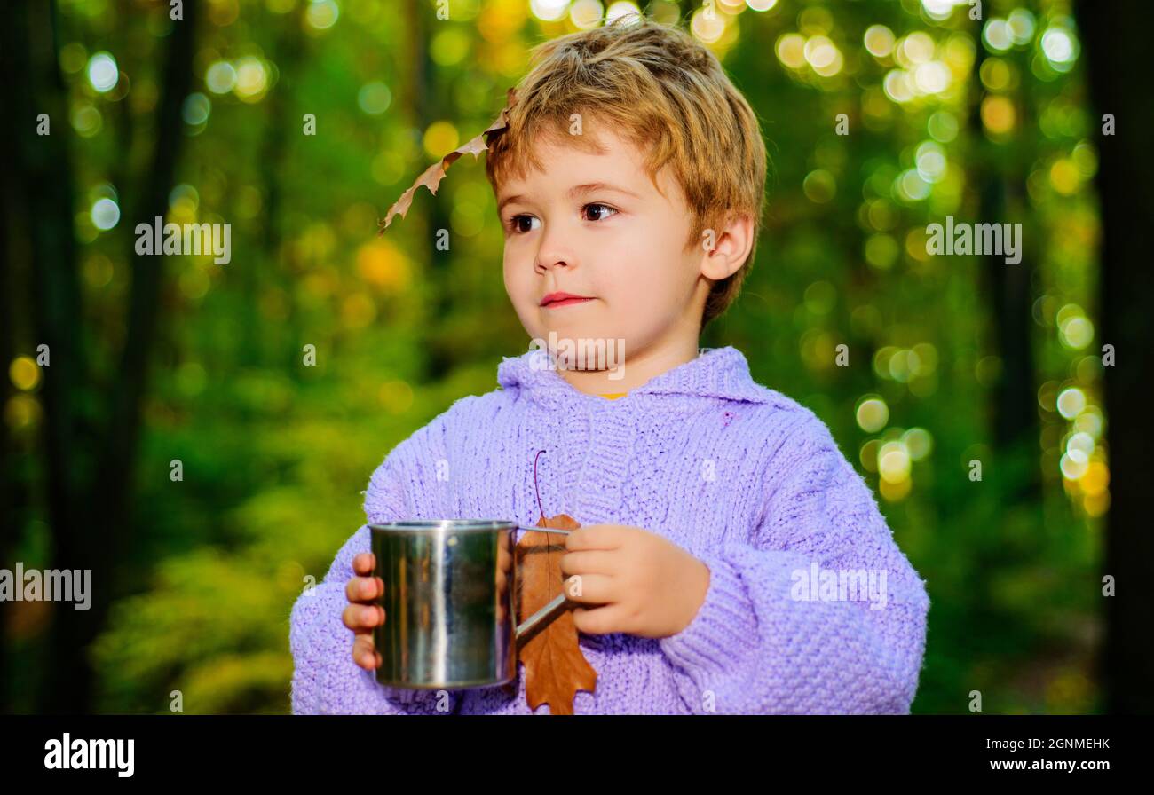 Bellissimo bambino in maglione con bevanda calda in autunno foresta. Ora di autunno. Carino bambino nel parco autunnale. Buona infanzia. Ragazzo su sfondo naturale autunno. Foto Stock
