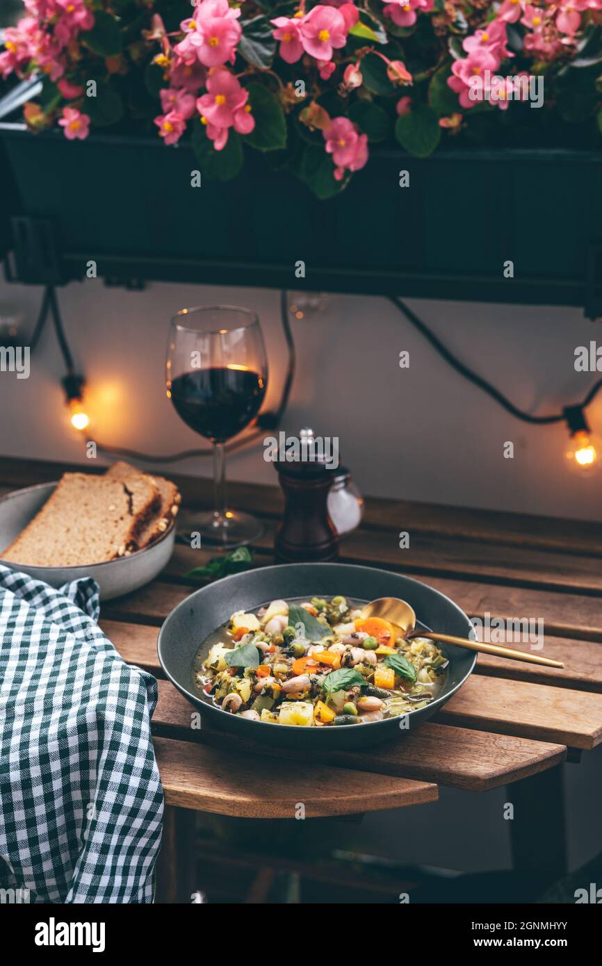 Piatto con deliziosa zuppa di minestroni e bicchiere di vino Foto Stock