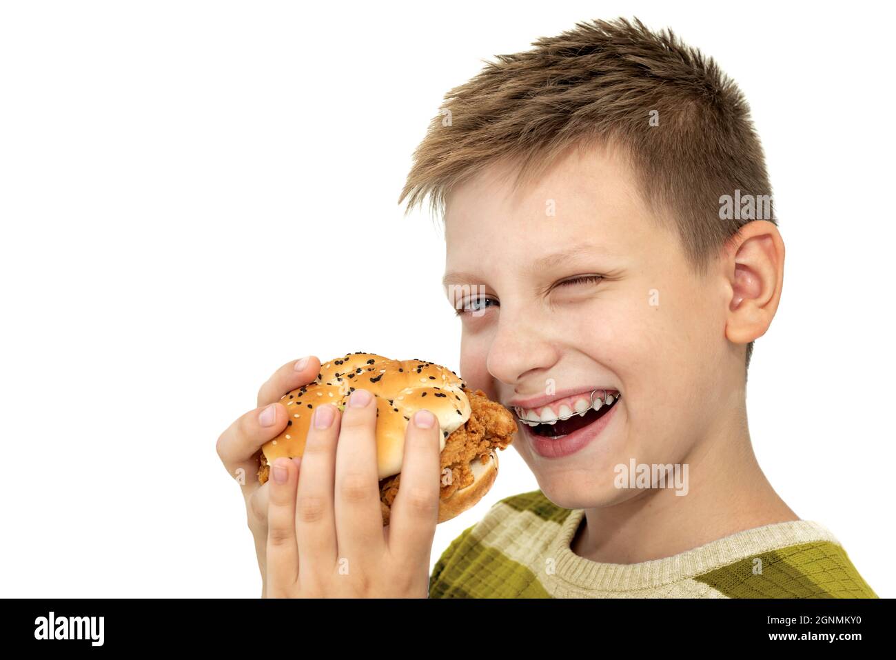 Ragazzo che mangia hamburger su sfondo bianco. Adolescente in bretelle. Cibo dannoso per i bambini Foto Stock