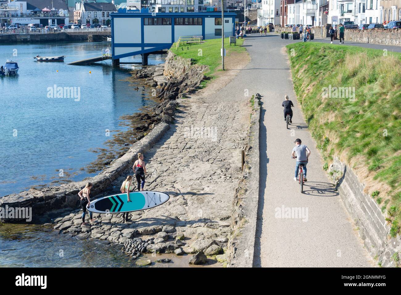 Paddleboarders e ciclisti a Portrush Harbour, Portrush (Port Rois), County Antrim, Irlanda del Nord, Regno Unito Foto Stock