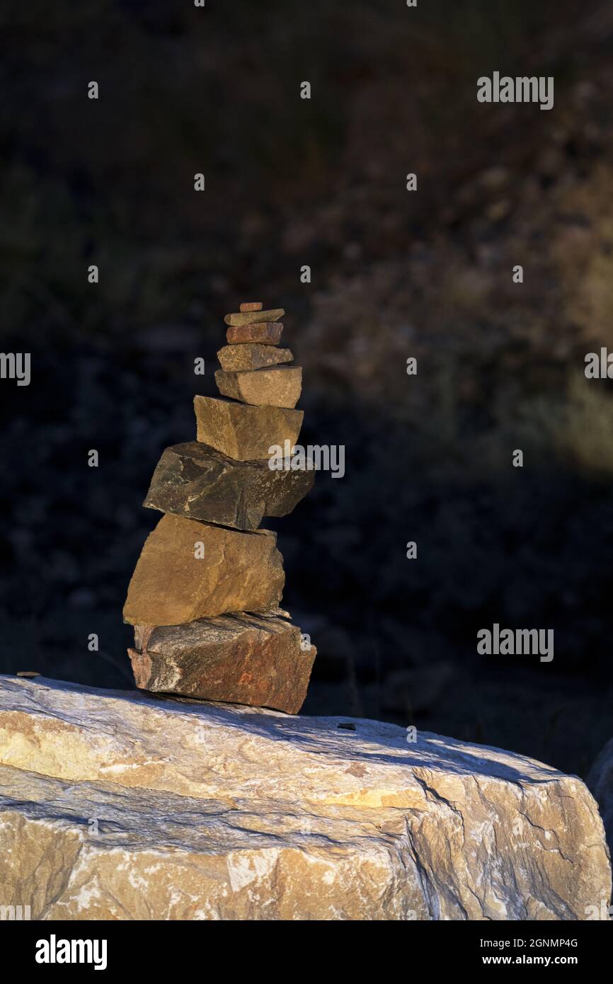 Pietre accuratamente impilate su roccia grande in formato fuoco e verticale selezionato con spazio di copia nell'area più scura dietro la torre di roccia piccola Foto Stock