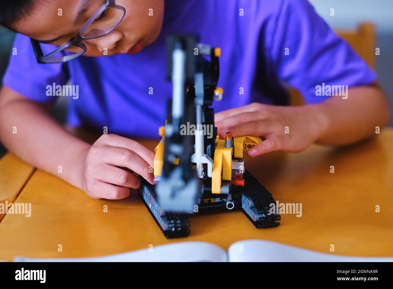 Bambino ragazzo costruzione meccanico Lego mattoni technic blocchi set sul tavolo a casa durante la pausa estiva. Scienza infantile, innovazione, ingegneria e creatività. Foto Stock