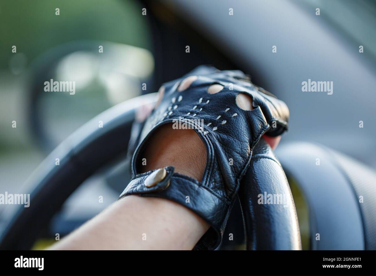 Le mani del conducente in guanti di pelle che guidano un'auto in movimento.  Donna che tiene il volante in guanti da corsa Foto stock - Alamy