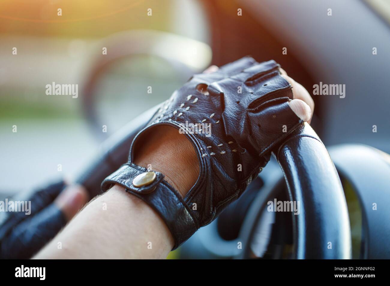 Le mani del conducente in guanti di pelle che guidano un'auto in movimento.  Donna che tiene il volante in guanti da corsa Foto stock - Alamy