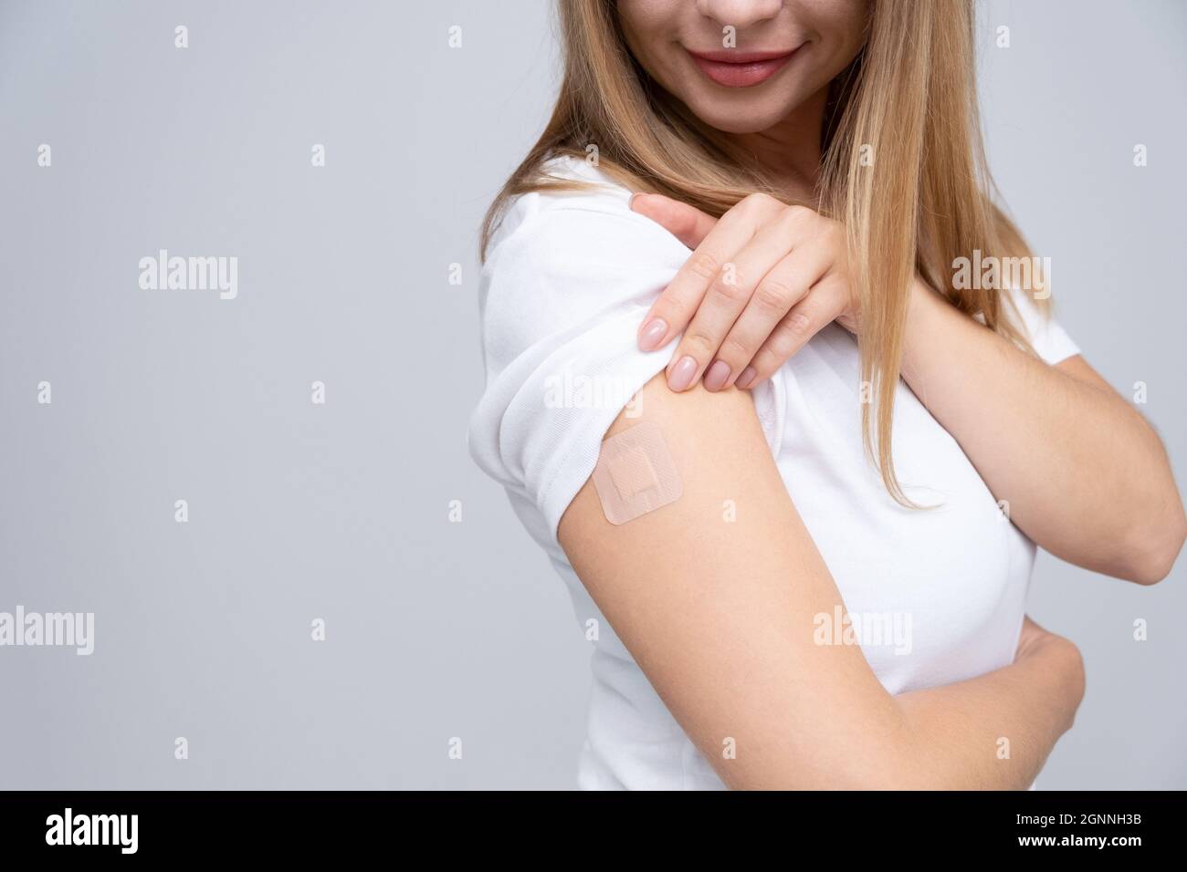 Donna e T-shirt bianca con un cerotto in mano si rallegra di ricevere una vaccinazione contro l'infezione da coronavirus Covid-19. Copia spazio. . Foto Stock