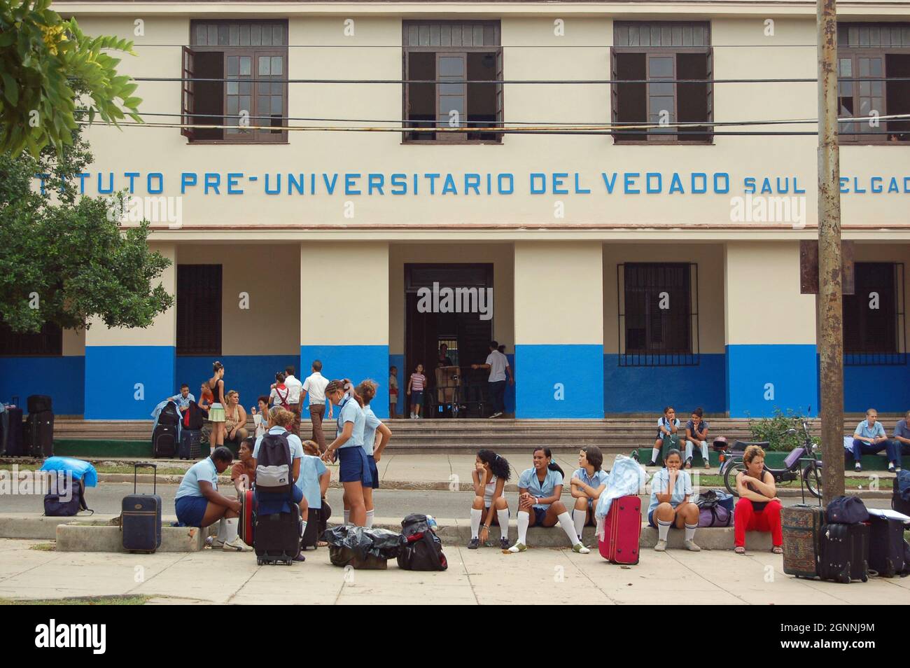 L'Avana, Cuba - 13 novembre 2006: Alunni e genitori con bagaglio in attesa di trasporto all'esterno dell'Istituto Pre-Universitario del Vedado in cit Foto Stock