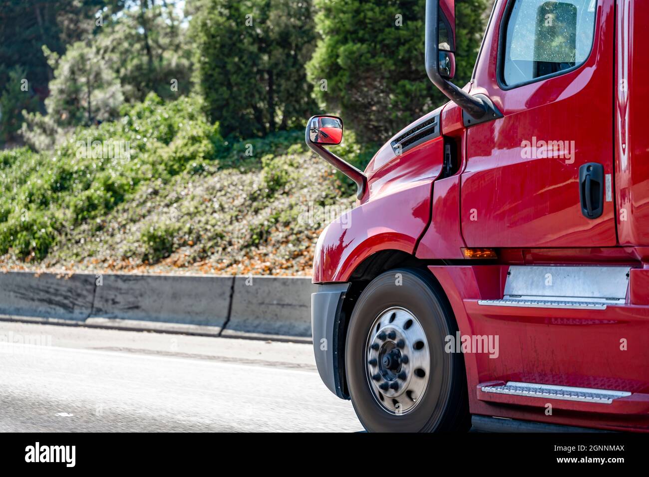 Parte anteriore del trattore semi-dumper da trasporto lungo rosso brillante e brillante con cabina alta e accessori in alluminio che funzionano su strada con foresta sulla a. Foto Stock