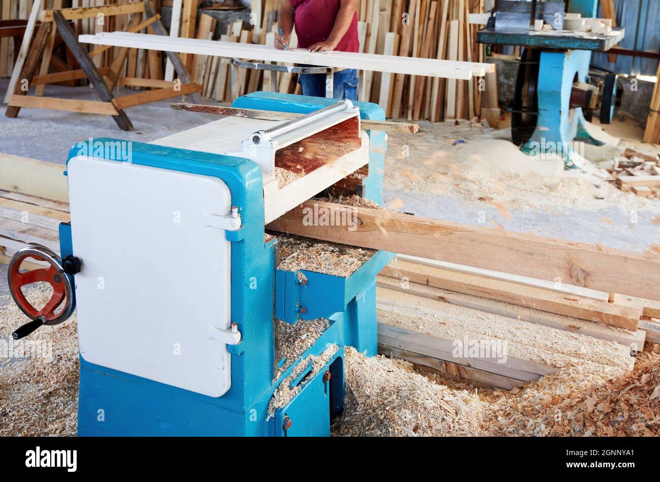 Una lastra di legno che passa attraverso la piallatrice di spessore in un'officina di carpenteria. Foto Stock