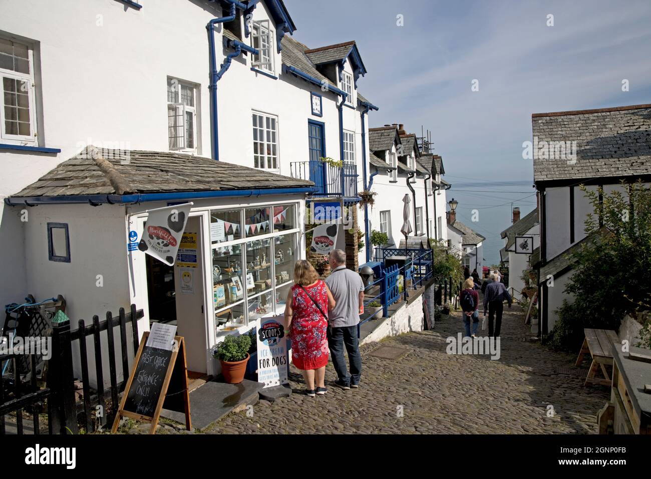 I visitatori che guardano nella finestra dell'ufficio postale su ripida strada lastricata nell'antico villaggio di Clovelly North Devon Foto Stock