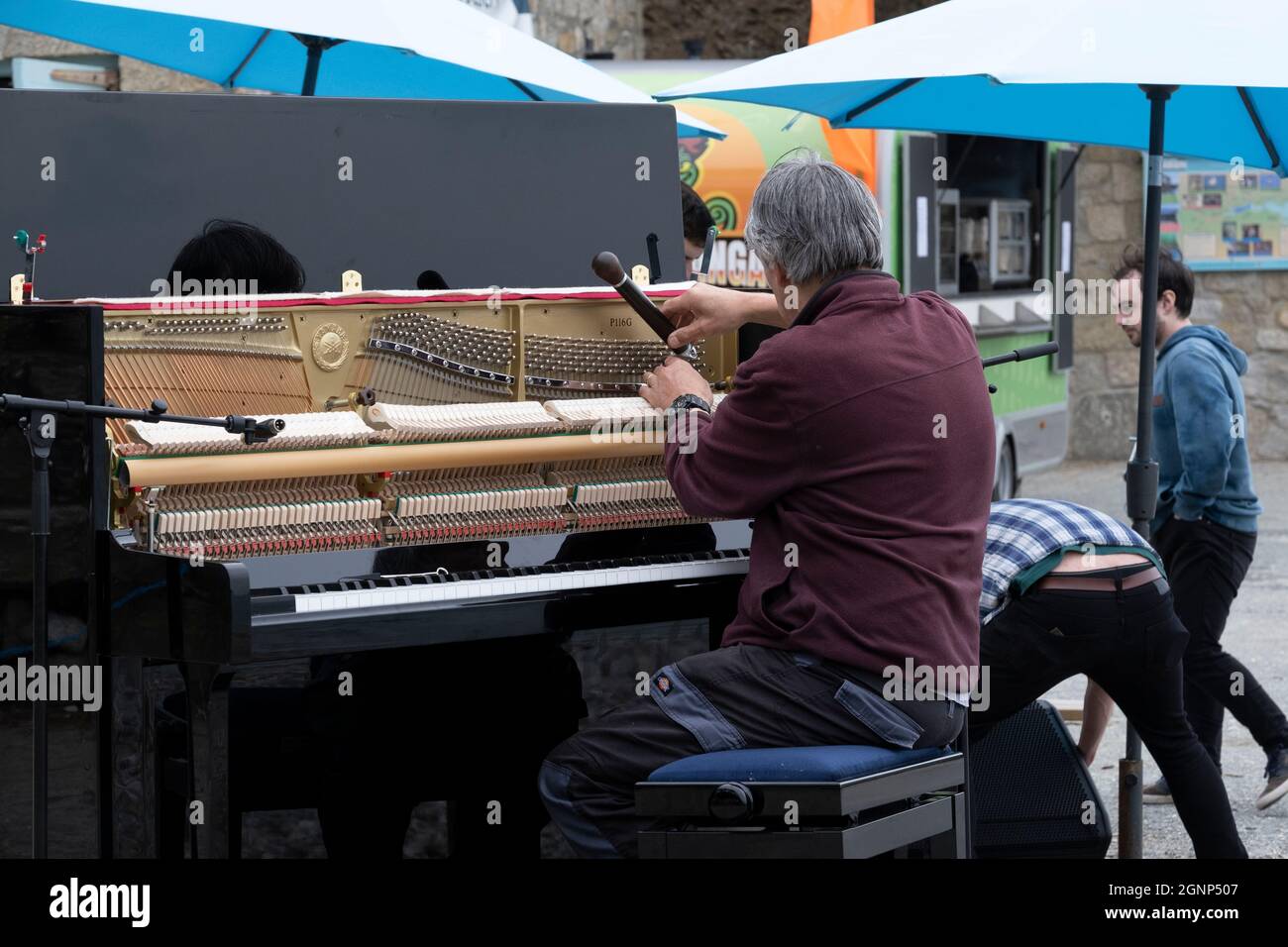 Un sintonizzatore per pianoforte che sintonizza un pianoforte verticale per una performance all'aperto. Foto Stock