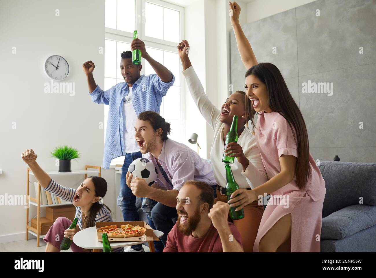 Gruppo di giovani tifosi che guardano il calcio in TV, urlando e sostenendo la squadra preferita Foto Stock