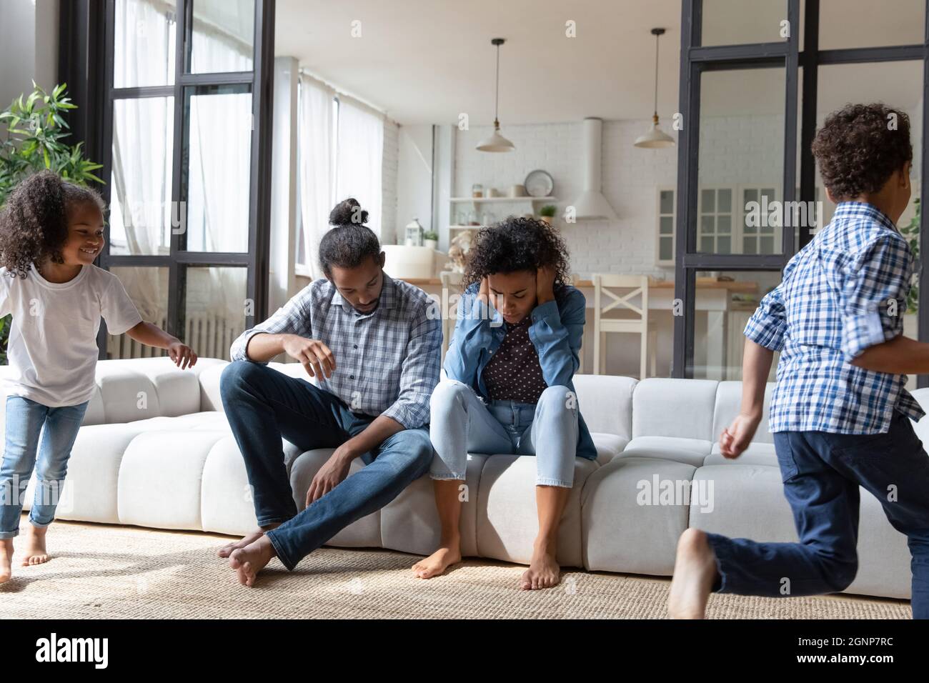 I genitori afroamericani si sentono esausti, figlia e figlio rumorosi che corrono Foto Stock