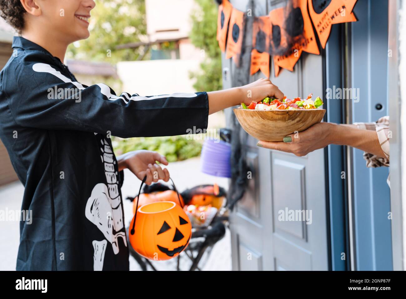 Ragazzo bianco vestito come trick-or-treating scheletro durante Halloween all'aperto Foto Stock