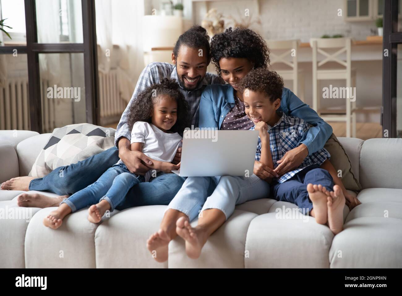 Felici genitori afroamericani con bambini che usano il computer portatile insieme Foto Stock