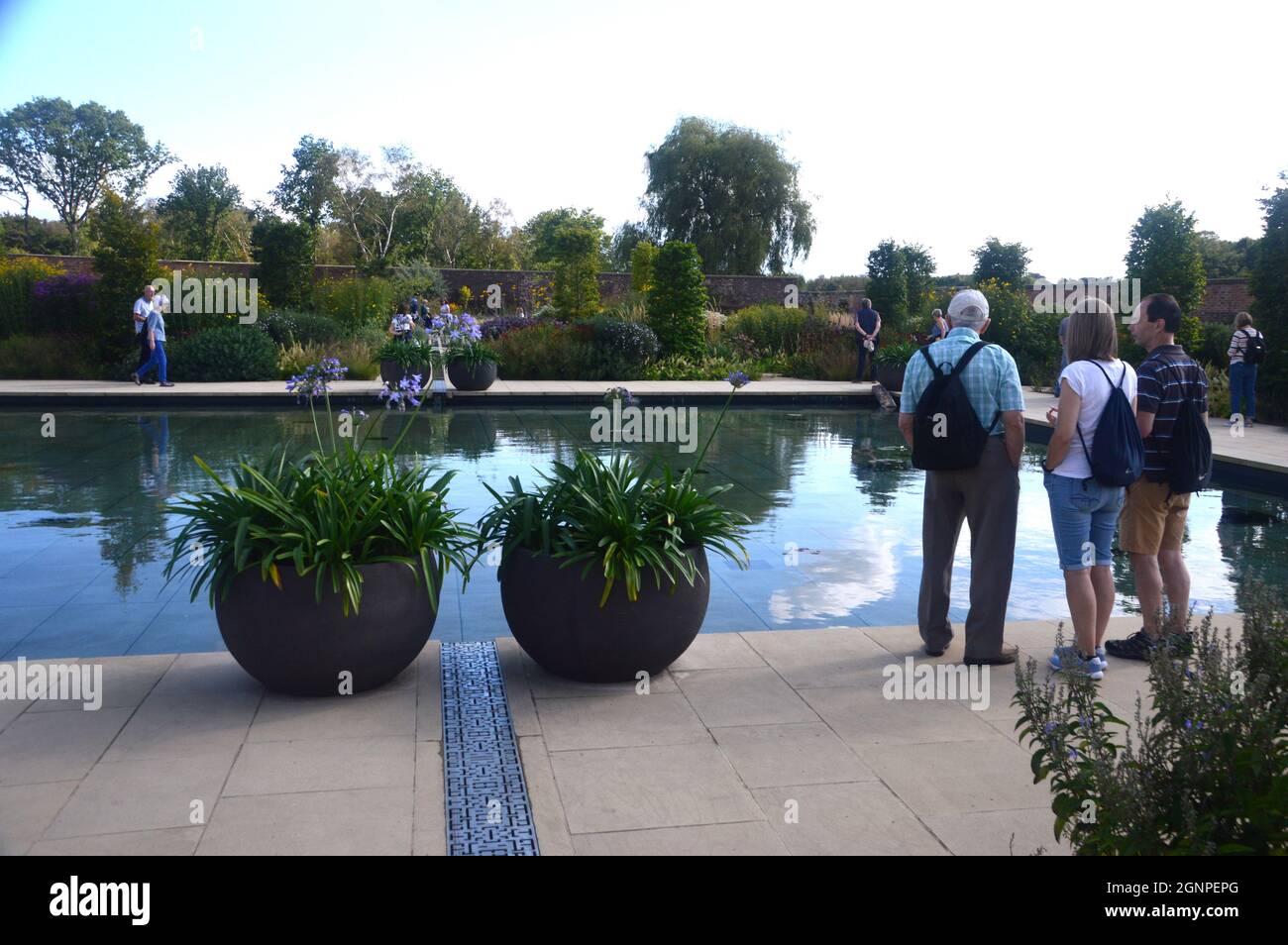 People & flowerpots by the Pond in the Victorian Weston Walled Paradise Garden at RHS Garden Bridgewater, Worsley, Manchester, UK. Foto Stock