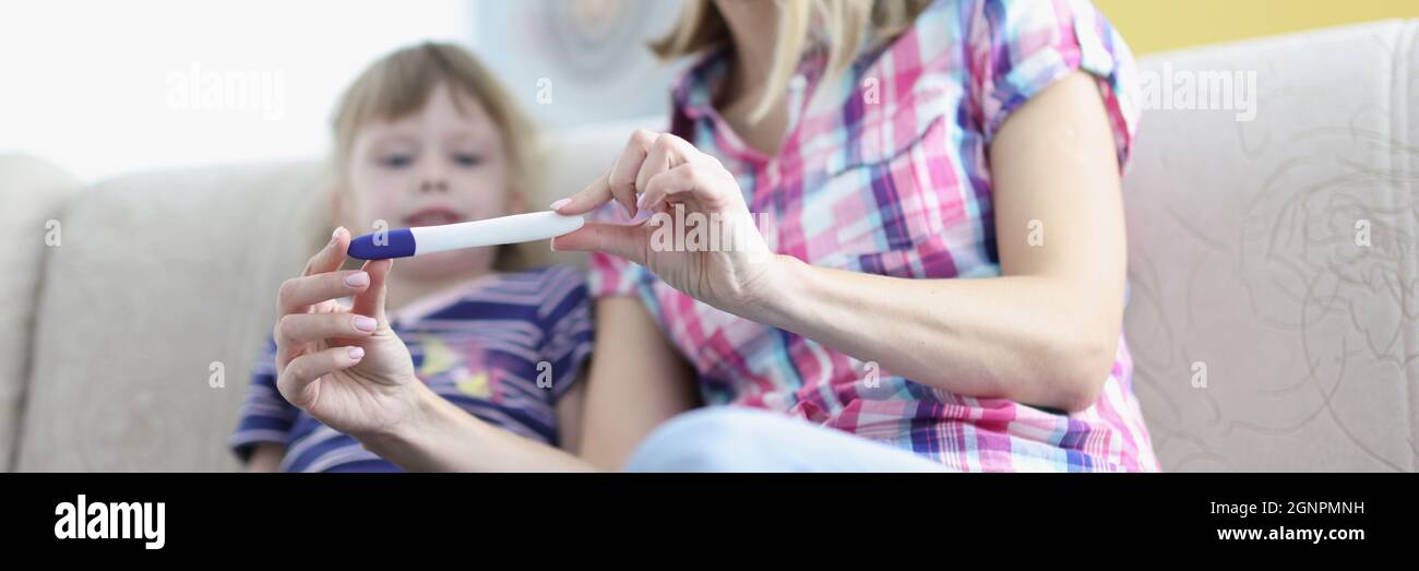 Madre che mostra la bambina positiva closeup test di gravidanza Foto Stock