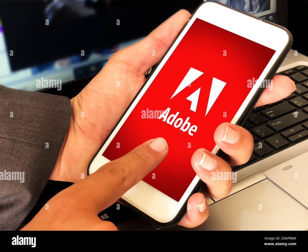 California, Stati Uniti-2021. L'applicazione Adobe Mobile si apre sullo schermo dello smartphone con l'uomo che tiene davanti al laptop. Redazionale adobe concept back Foto Stock