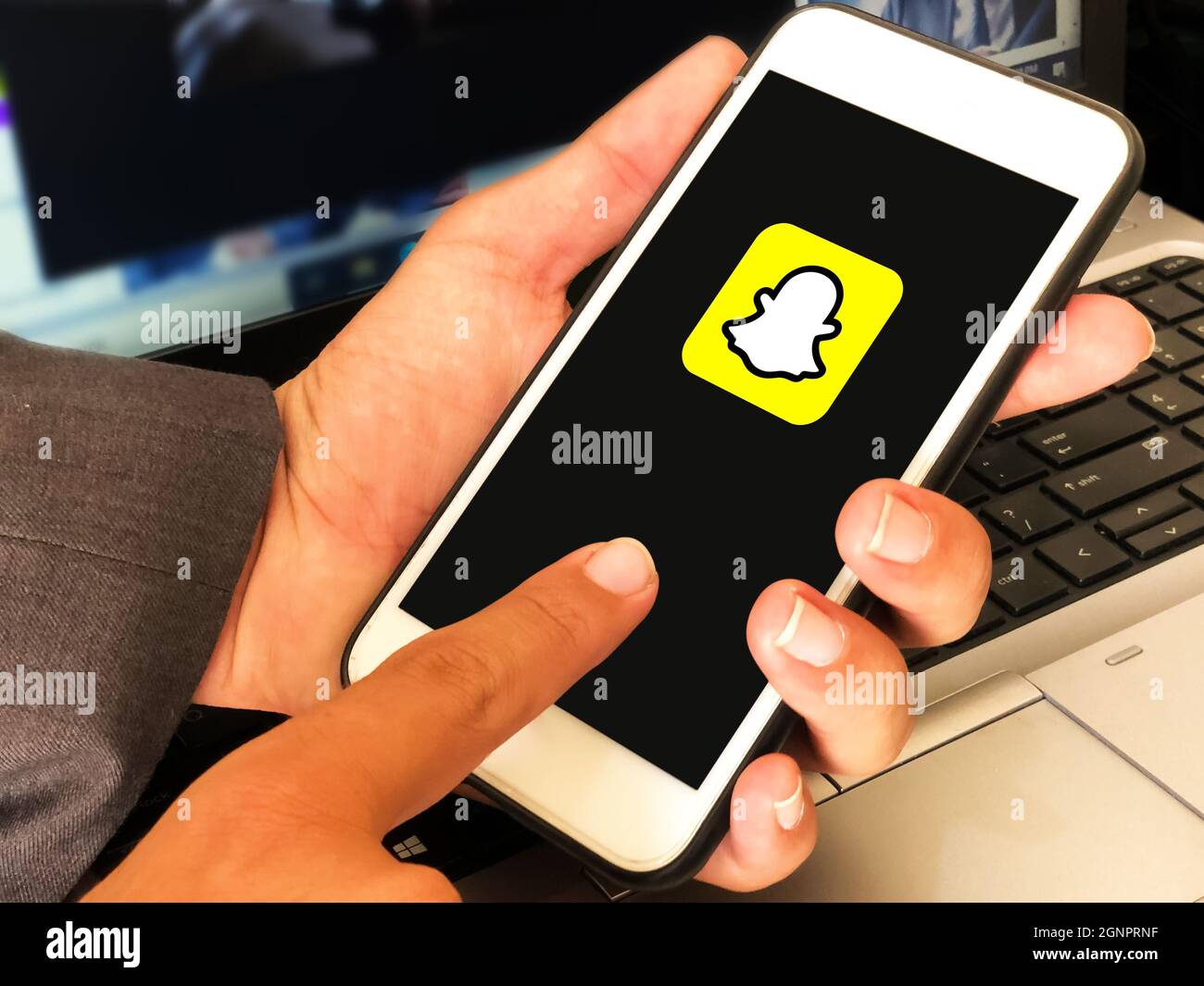 9.20.2021. New York, Stati Uniti. Logo Snapchat visualizzato sullo schermo del cellulare con l'uomo che tiene davanti al laptop. Concetto editoriale dei social media Foto Stock