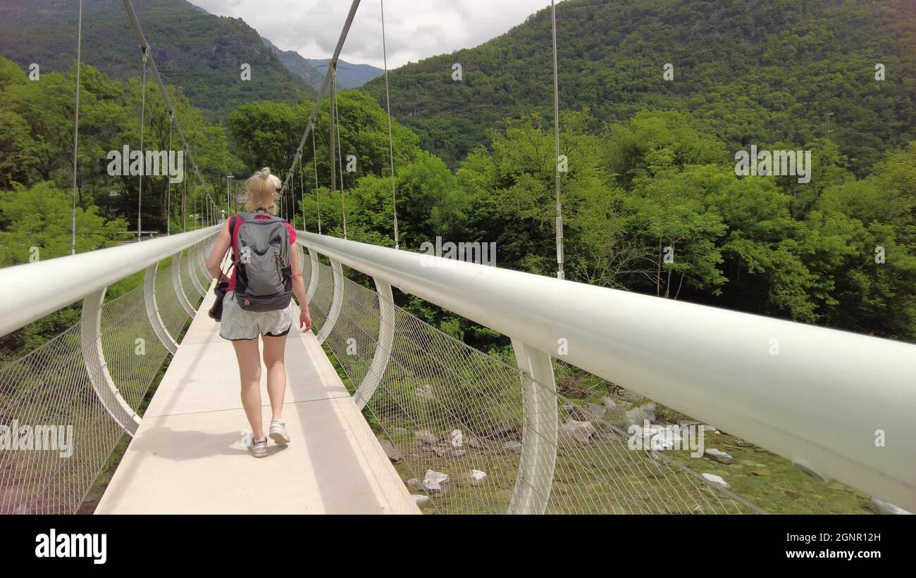 Donna zaino in spalla che cammina sul ponte del fiume Maggia in Svizzera. Valle Vallemaggia del Cantone Ticino, nei pressi delle città svizzere di Locarno e Ascona. Foto Stock