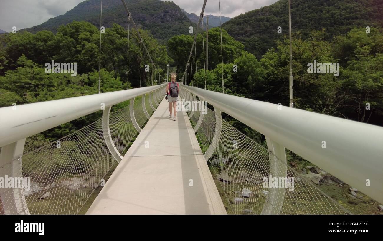 Donna zaino in spalla che cammina sul ponte del fiume Maggia in Svizzera. Valle Vallemaggia del Cantone Ticino, nei pressi delle città svizzere di Locarno e Ascona. Foto Stock
