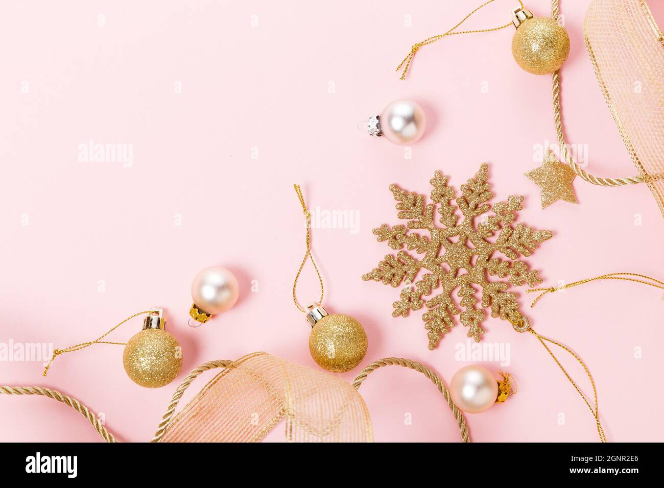 Golden bello scintillante natale decorativi giocattoli su sfondo rosa pastello. Foto Stock