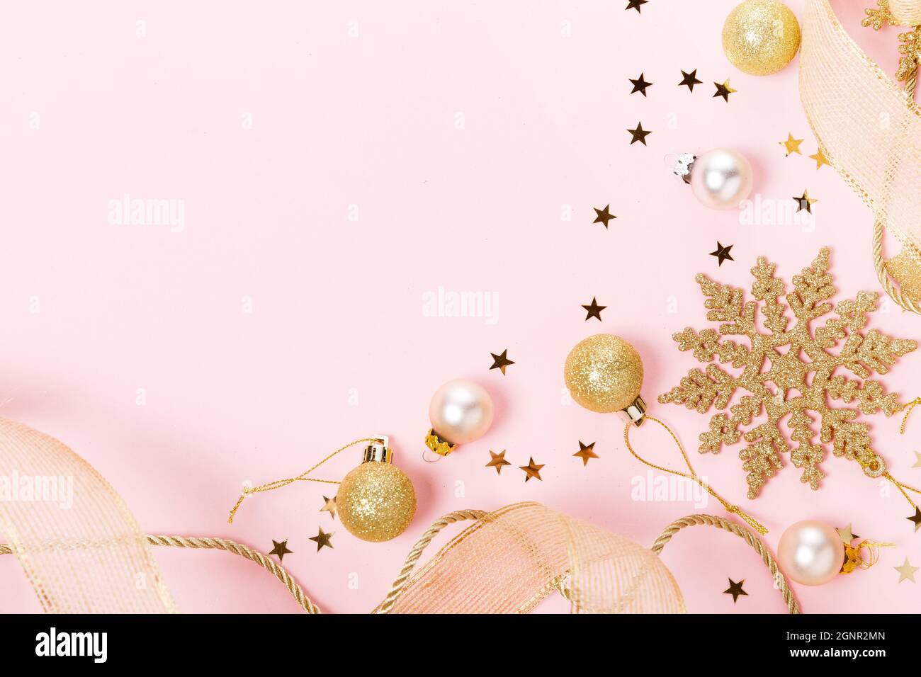 Golden bello scintillante natale decorativi giocattoli su sfondo rosa pastello. Foto Stock