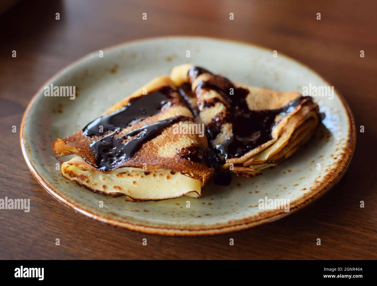 Le crepes sono su un piatto, sgocciolato di cioccolato. Pancake sottili. Dolce dessert. Foto Stock