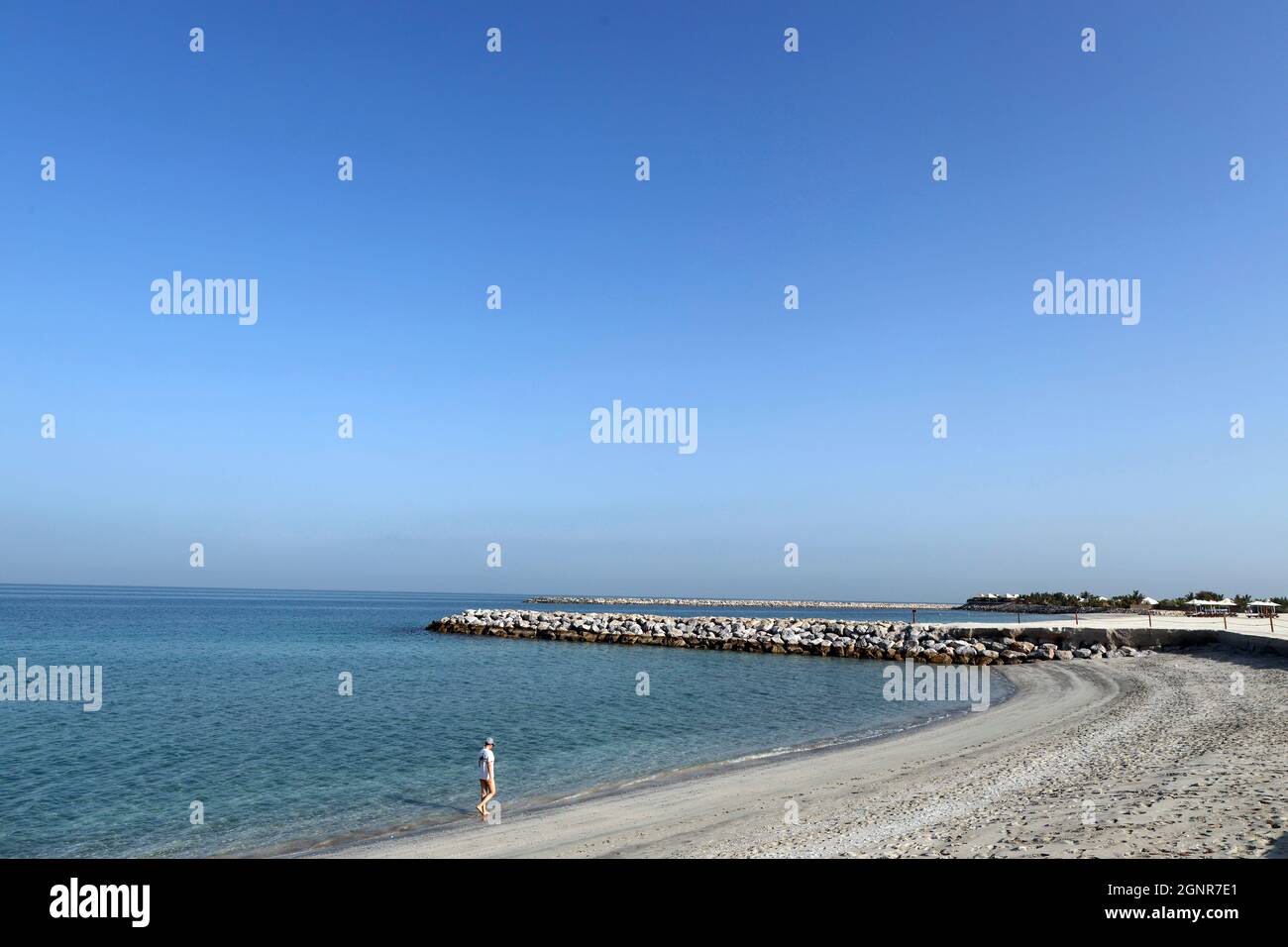 Al Hamra Beach sul Golfo Arabo a Ras al Khaimah. Donna che cammina da sola sulla spiaggia. Emirati Arabi Uniti. Foto Stock