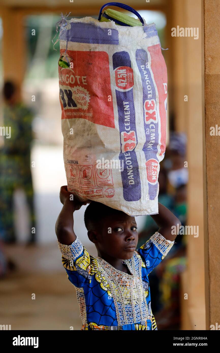 Ragazza che porta una borsa equilibrata sulla testa. Benin. Foto Stock