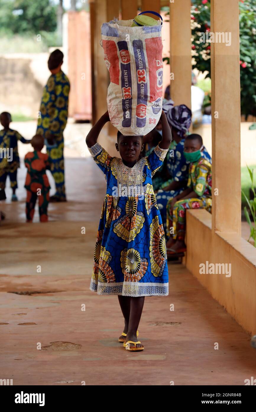 Ragazza che porta una borsa equilibrata sulla testa. Benin. Foto Stock