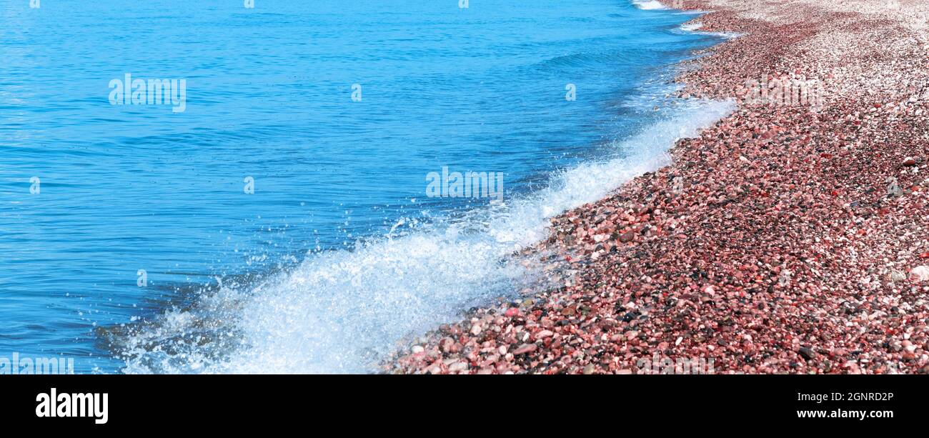 Frammento di costa marina con ciottoli rossi Foto Stock