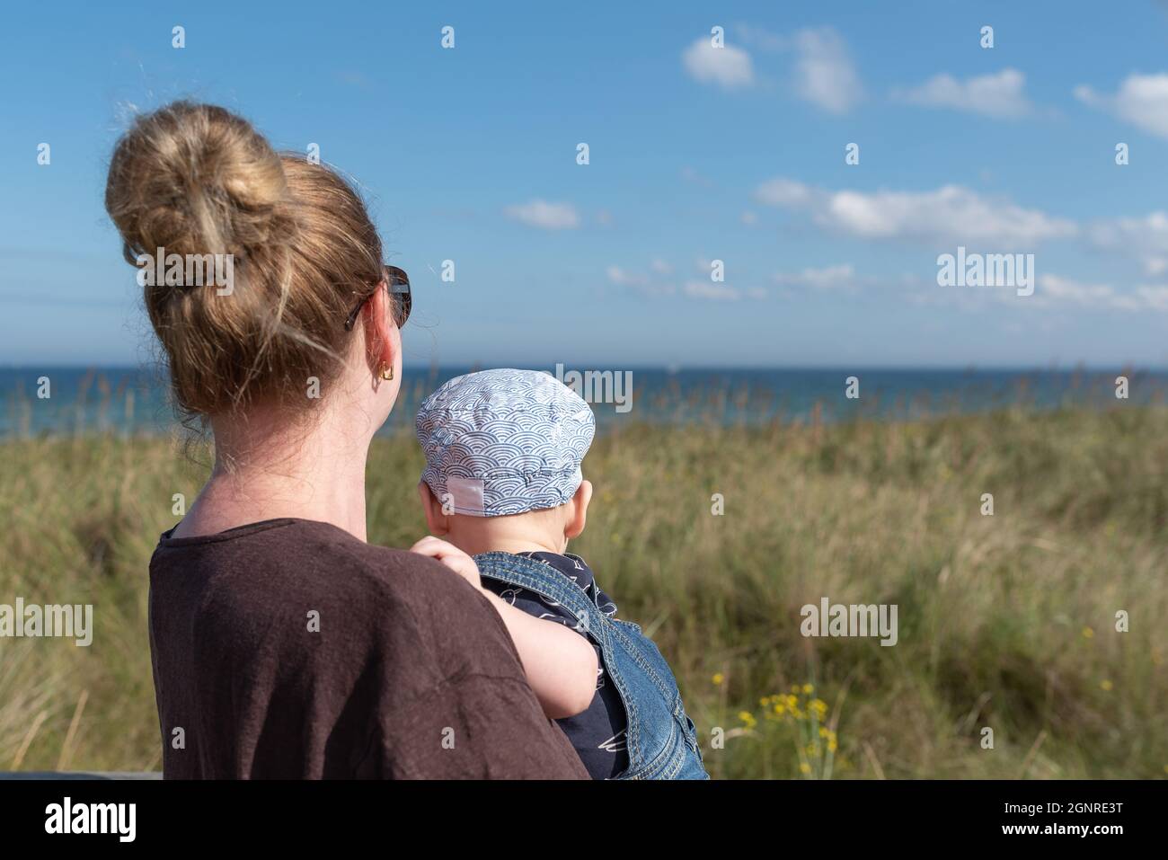 madre che porta bambino ragazzo guardando il mare Foto Stock