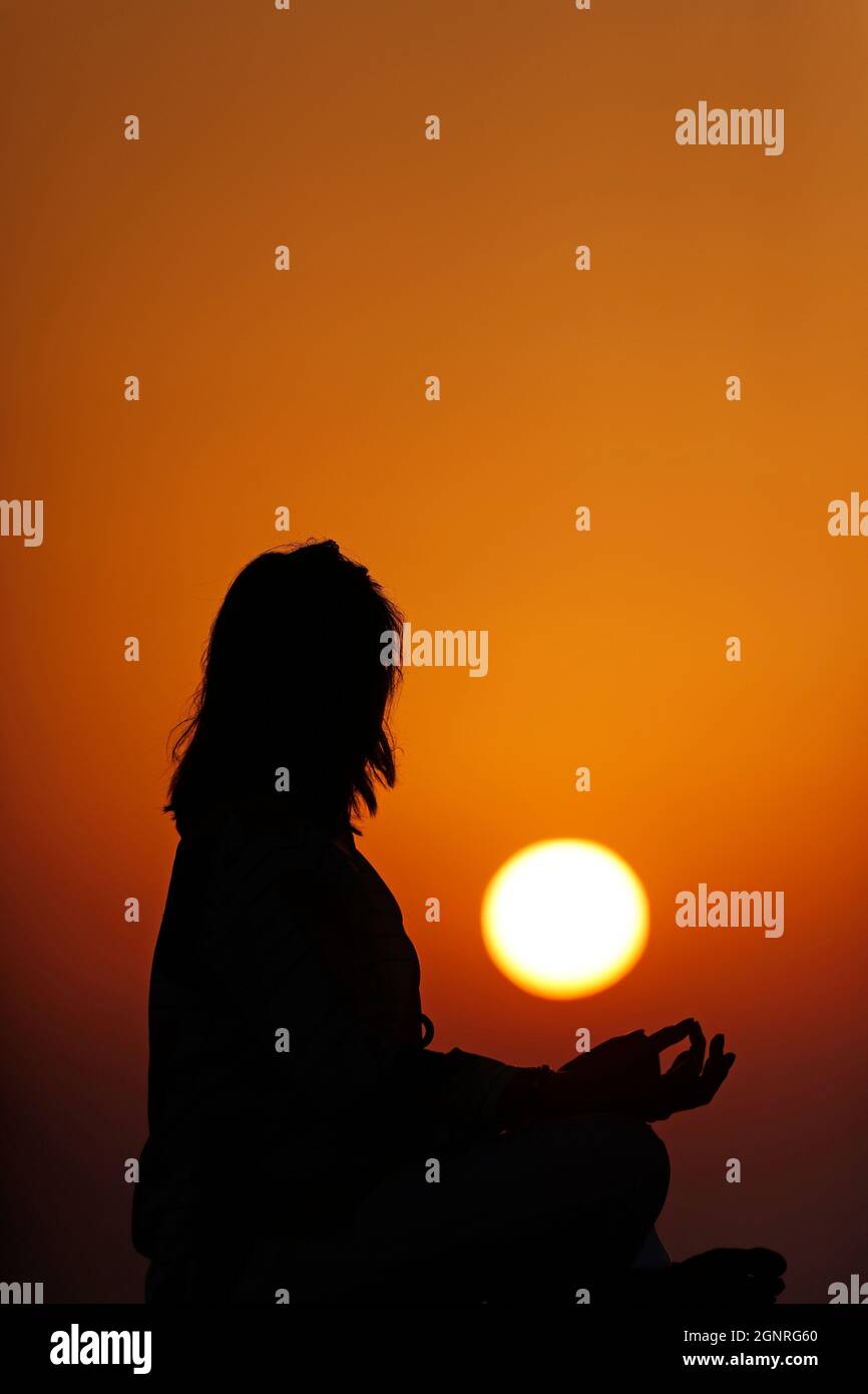 Donna che pratica yoga posa e meditazione al tramonto. Concetto di silenzio e relax. Foto Stock