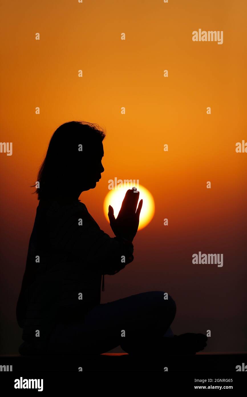 Donna che pratica yoga posa e meditazione al tramonto. Concetto di silenzio e relax. Foto Stock