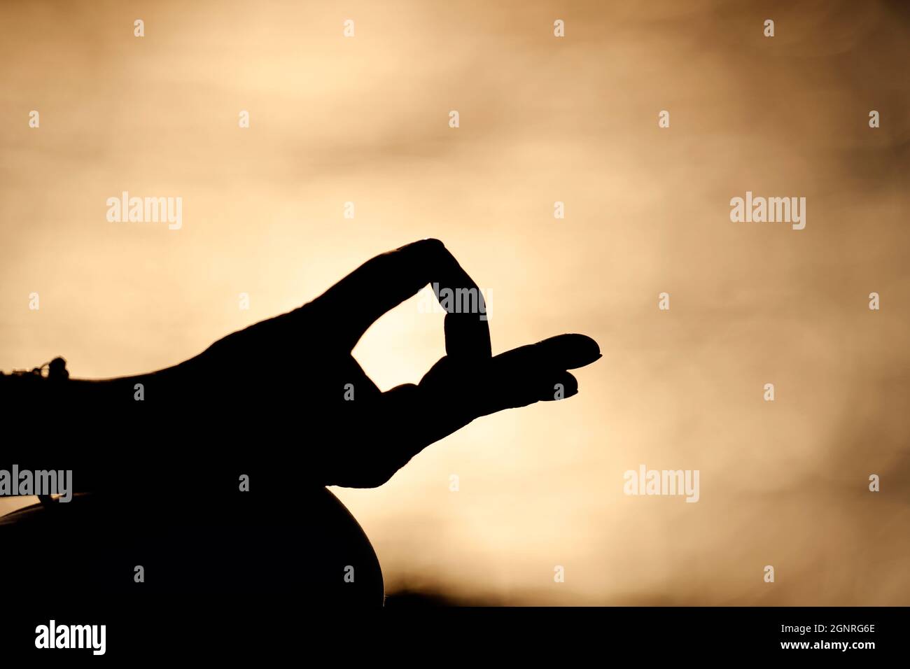 Primo piano mano di giovane donna pratica meditazione in posizione lotus. Yoga al tramonto. Foto Stock