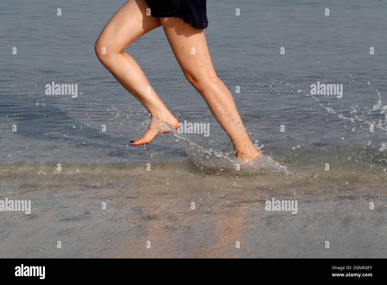 Sport. Donna che corre a piedi nudi sulla spiaggia. Emirati Arabi Uniti. Foto Stock