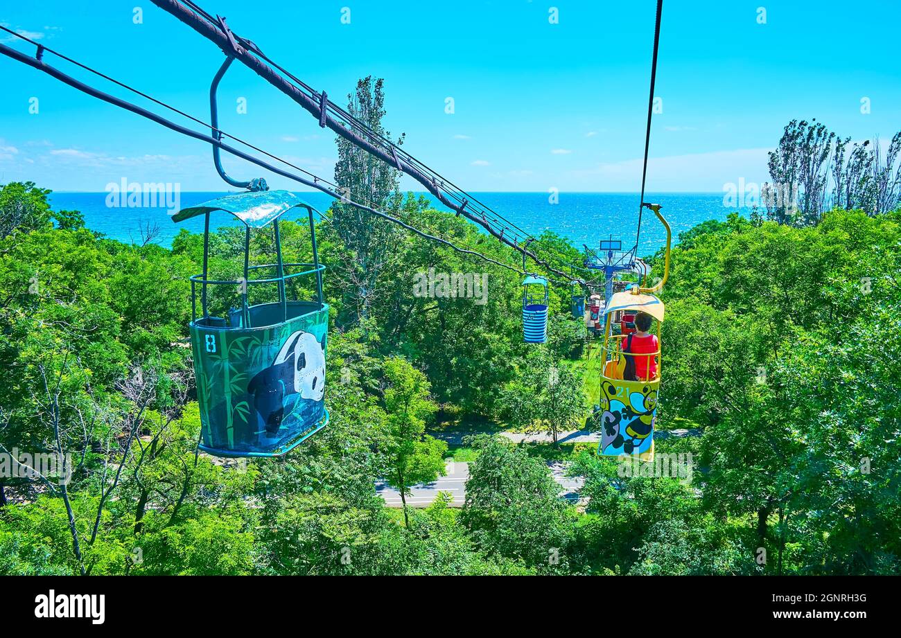 Godetevi il giro in cabinovia retrò sopra la lussureggiante foresta verde con una vista della costa del Mar Nero all'orizzonte, Odessa, Ucraina Foto Stock