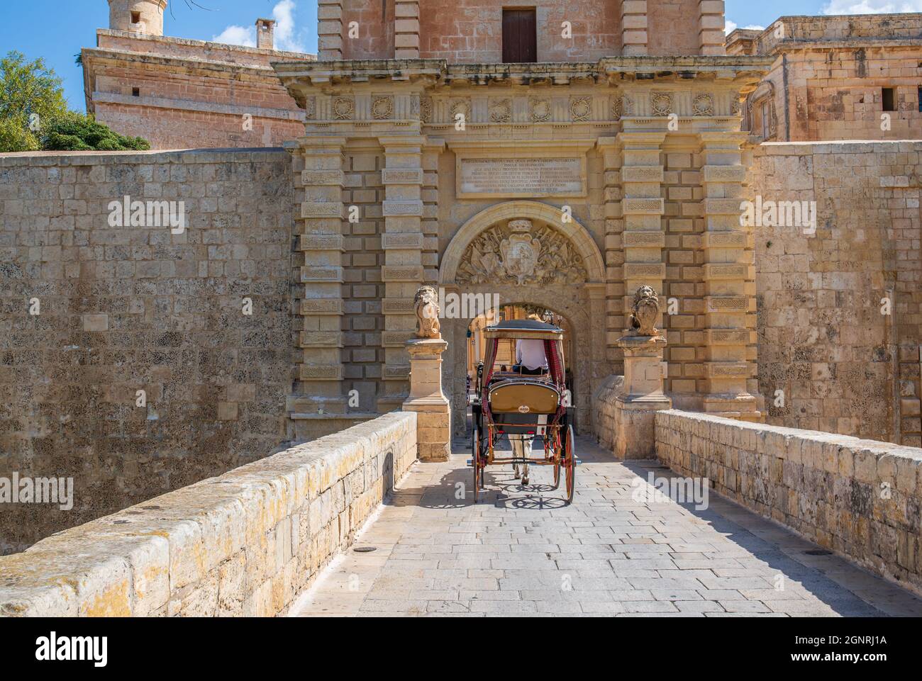 Mdina Malta Luglio 27 2017 l'ingresso principale con cancello e carrozza trainata da cavalli che passa sopra il ponte di pietra Foto Stock