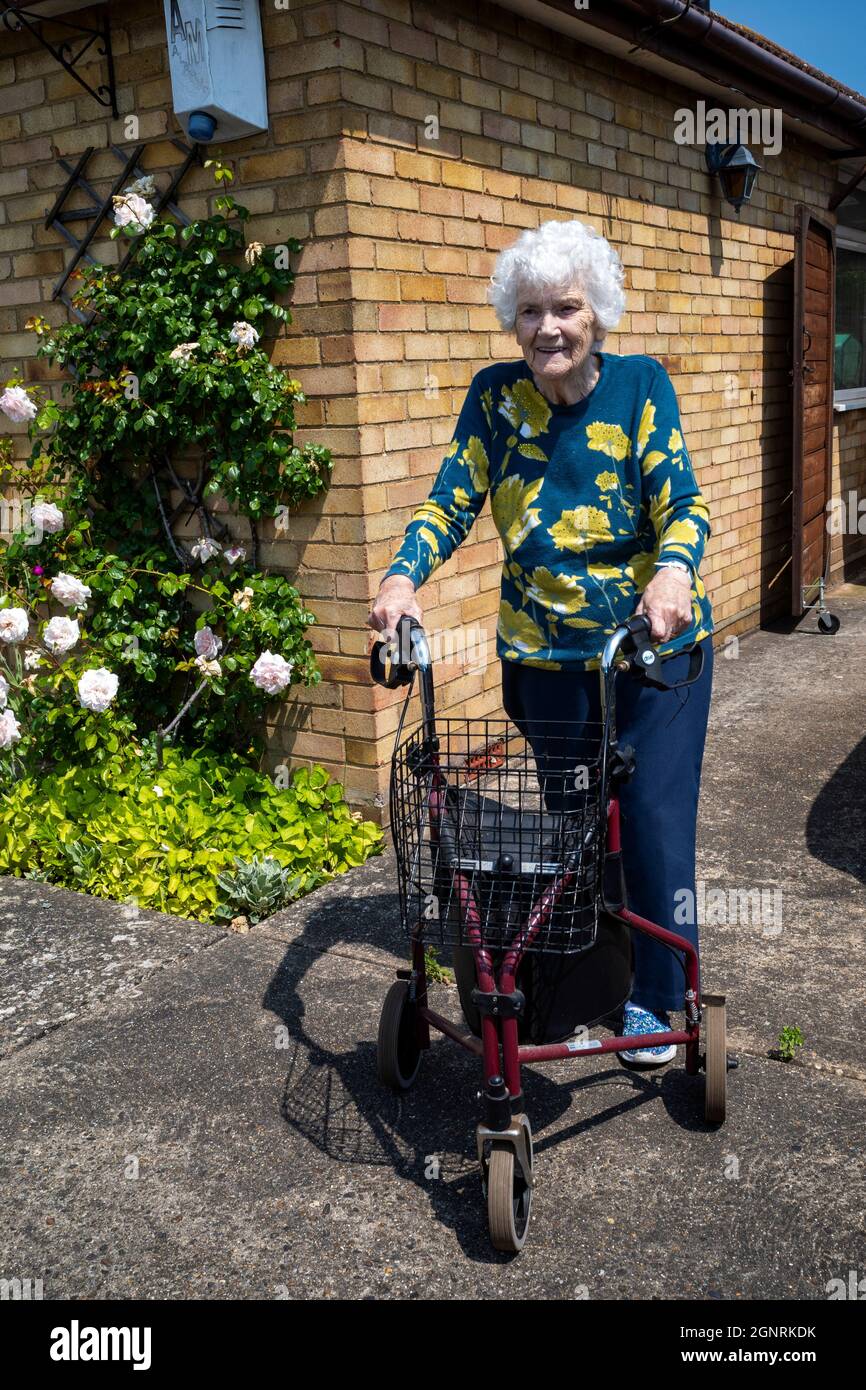 Donna anziana che utilizza un telaio a piedi con ruote Foto Stock