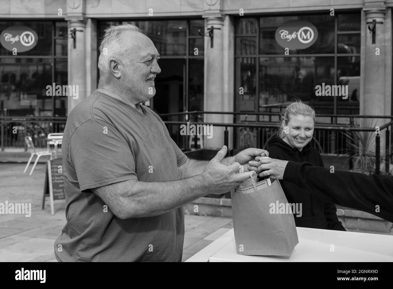 Mentre passeggi per il centro di Harrogate, un uomo in una t-shirt riceve una lattina di soda gratuita, che egli mette nella sua borsa di carta, Regno Unito. Foto Stock